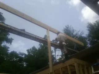 Carpenter setting a ridge beam over a new addition frame — Ice Dam Removal by Roofing Brothers in Madisonville