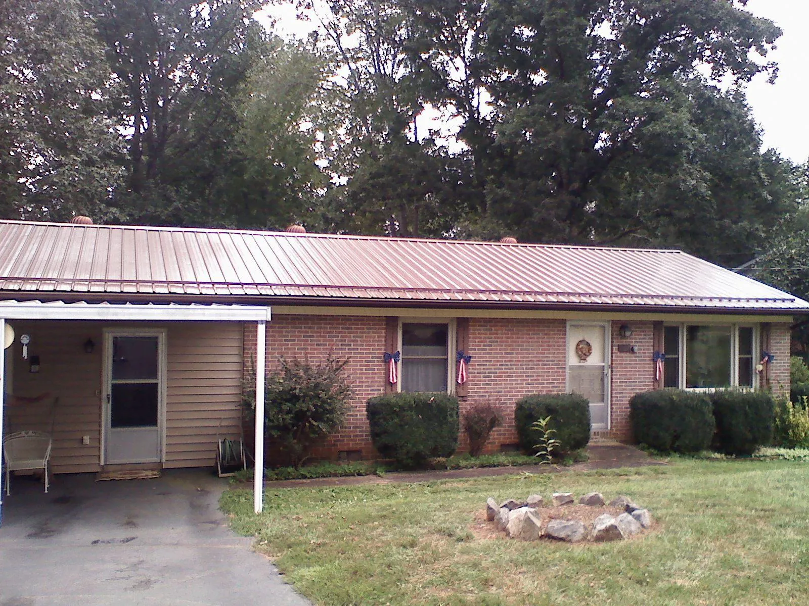 Bronze metal roof and carport on a brick ranch home — Roof Repair work by our crew in Madisonville